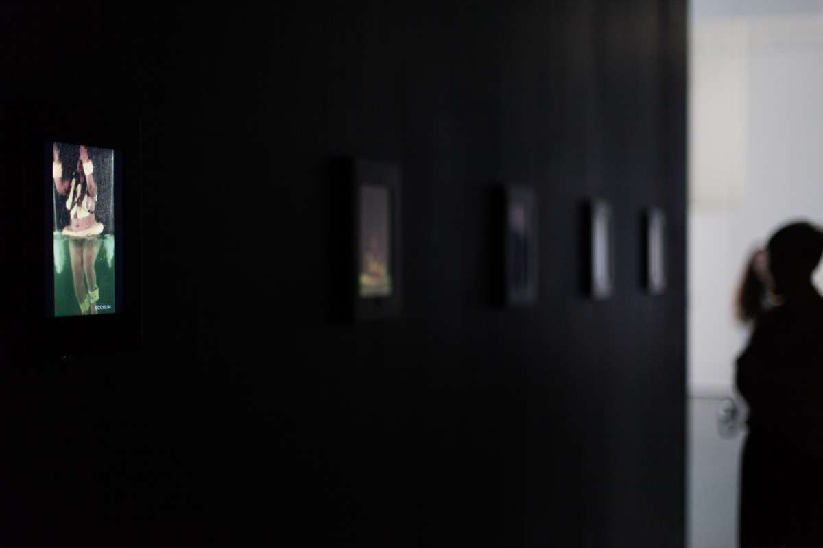 A black wall appears out of focus, with digital screens on it.