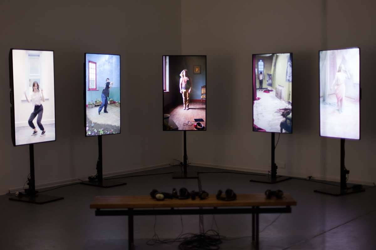 Five digital screens sit side by side, each showing a different person, dancing in a different home setting.