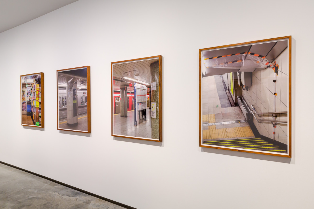 Four framed photographs hang on a white wall.