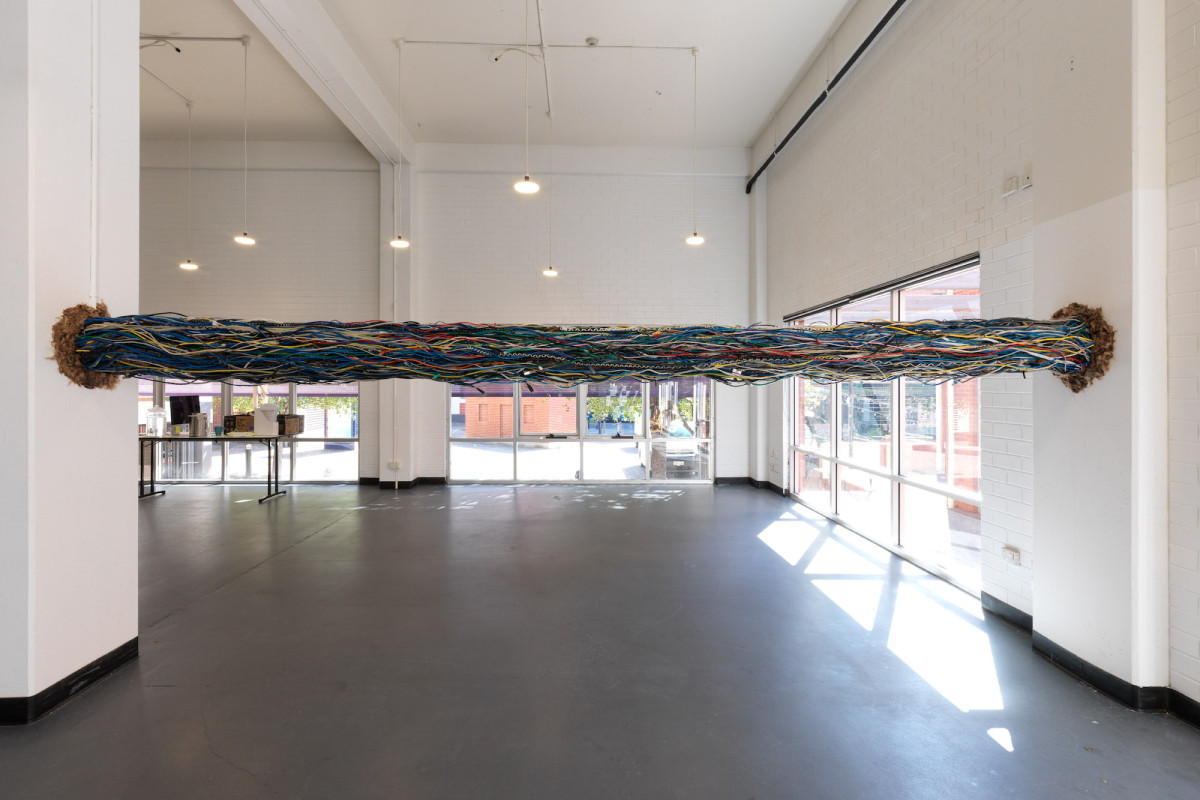 A sculpture comprised of a collective mass of linear wires installed between two gallery walls 2 meters above ground level.