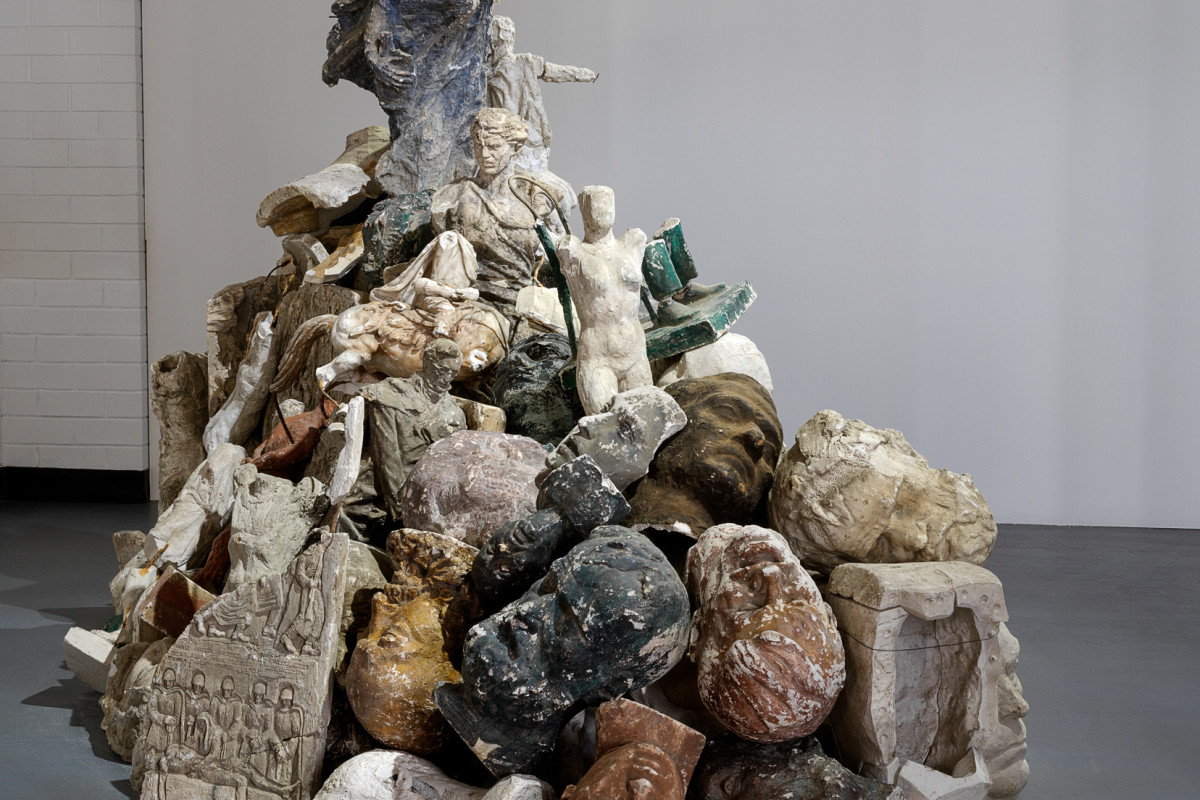 Large sculpture consisting of a pile of stone heads and stone figures.