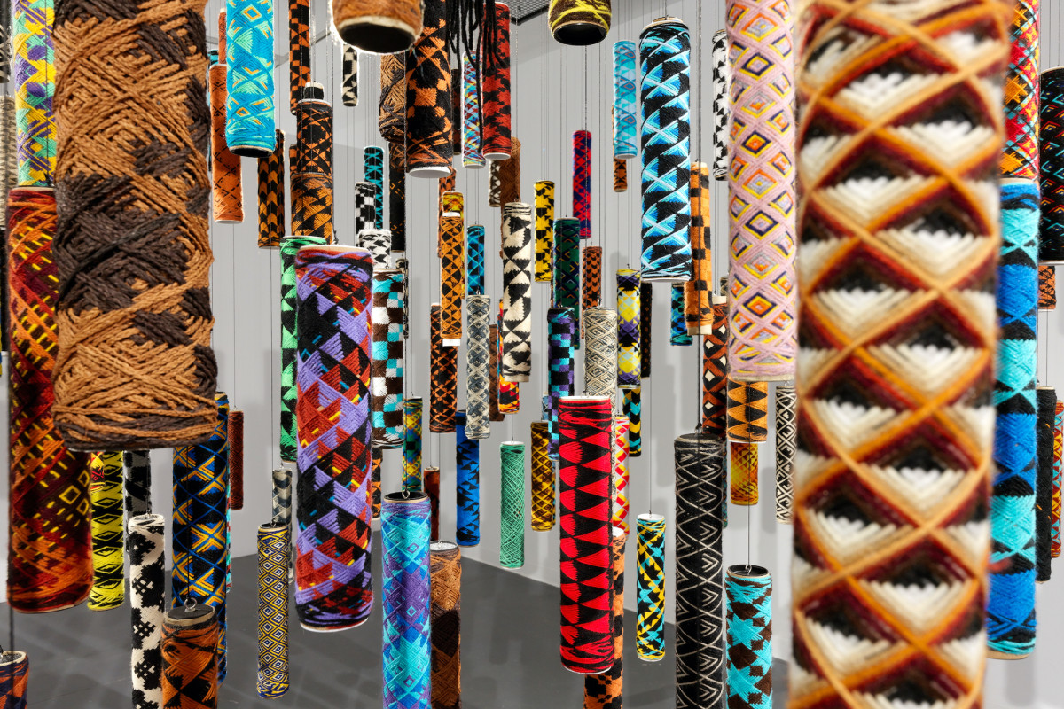 Many suspended cylindrical objects of many colours and patterns.