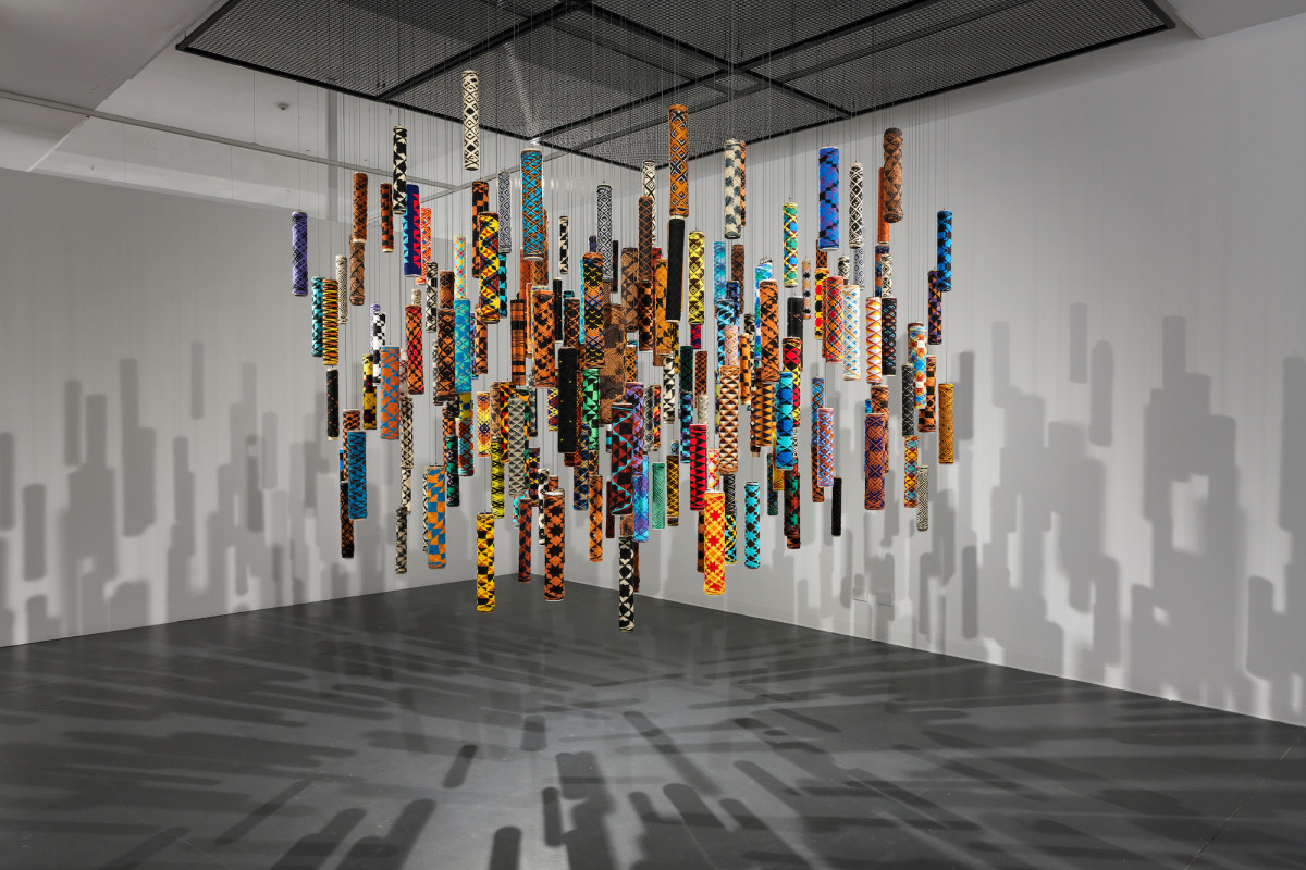 Many suspended cylindrical objects of many colours and patterns.