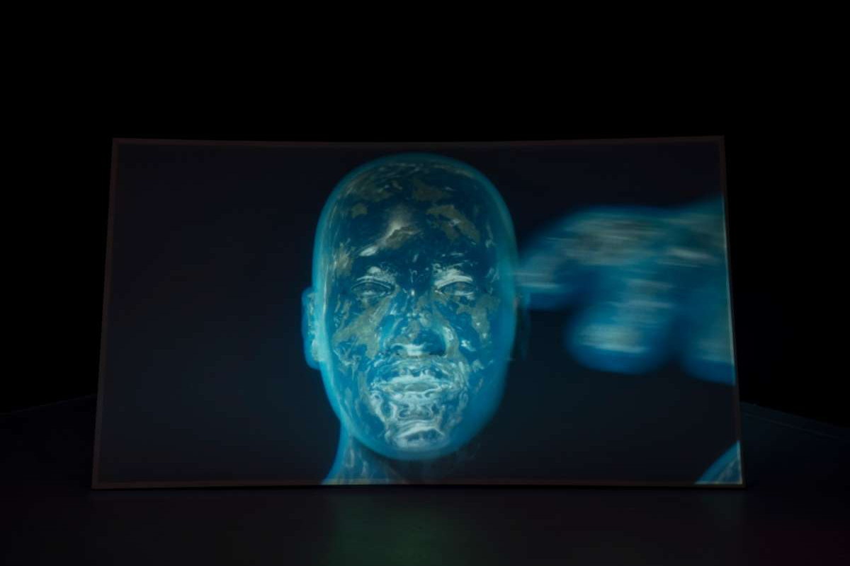 A still from a video shows the shape of a human face, made up of the blue, green and white swirls of planet earth when viewed from space.