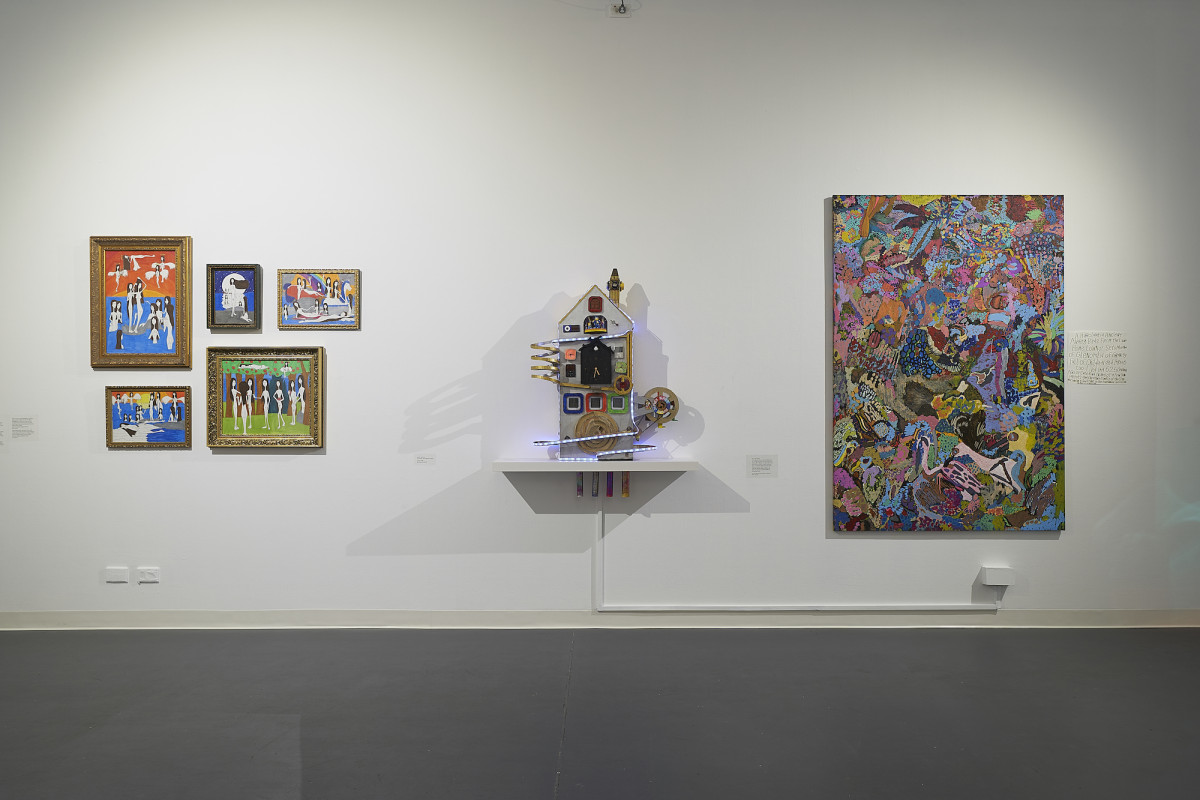 Three works displayed on white, gallery wall. To the left five collaged hang colourful framed paintings, in the middle a sculpture on a shelf and to the right, a large canvas abstract painting.