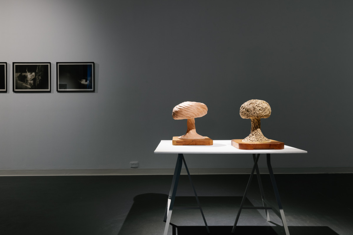Spotlight illuminates a table with two wooden mushroom bomb sculptures.