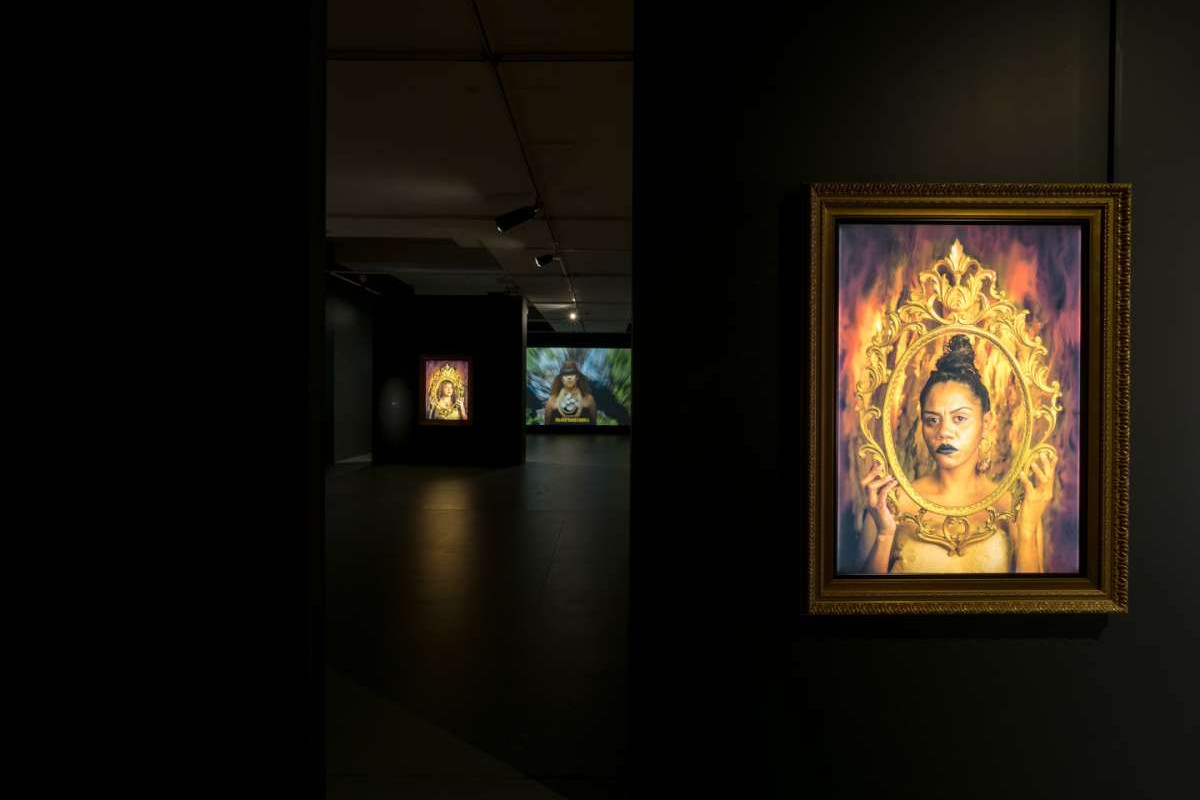 A framed photograph of a woman with black lipstick, holding an ornate frame up to her face.