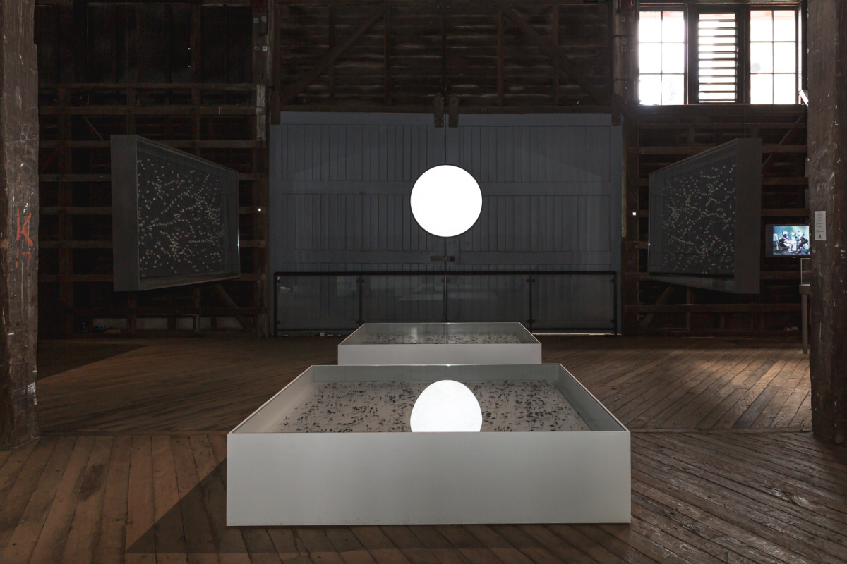 Two white display cabinets sit on the floor; two black display cabinets hang from ceiling. An orbe shines brightly above and between the cabinets.