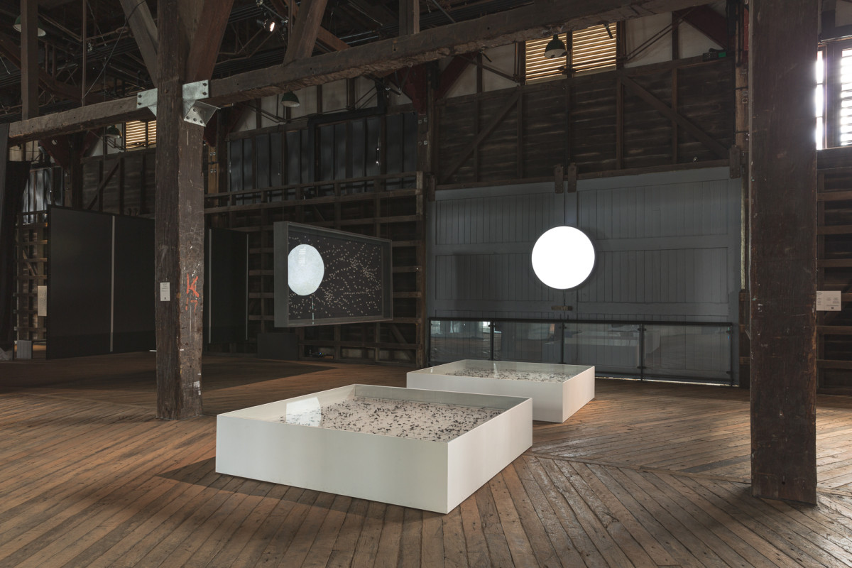 Two white display cabinets sit on the floor; two black display cabinets hang from ceiling. An orbe shines brightly above and between the cabinets.