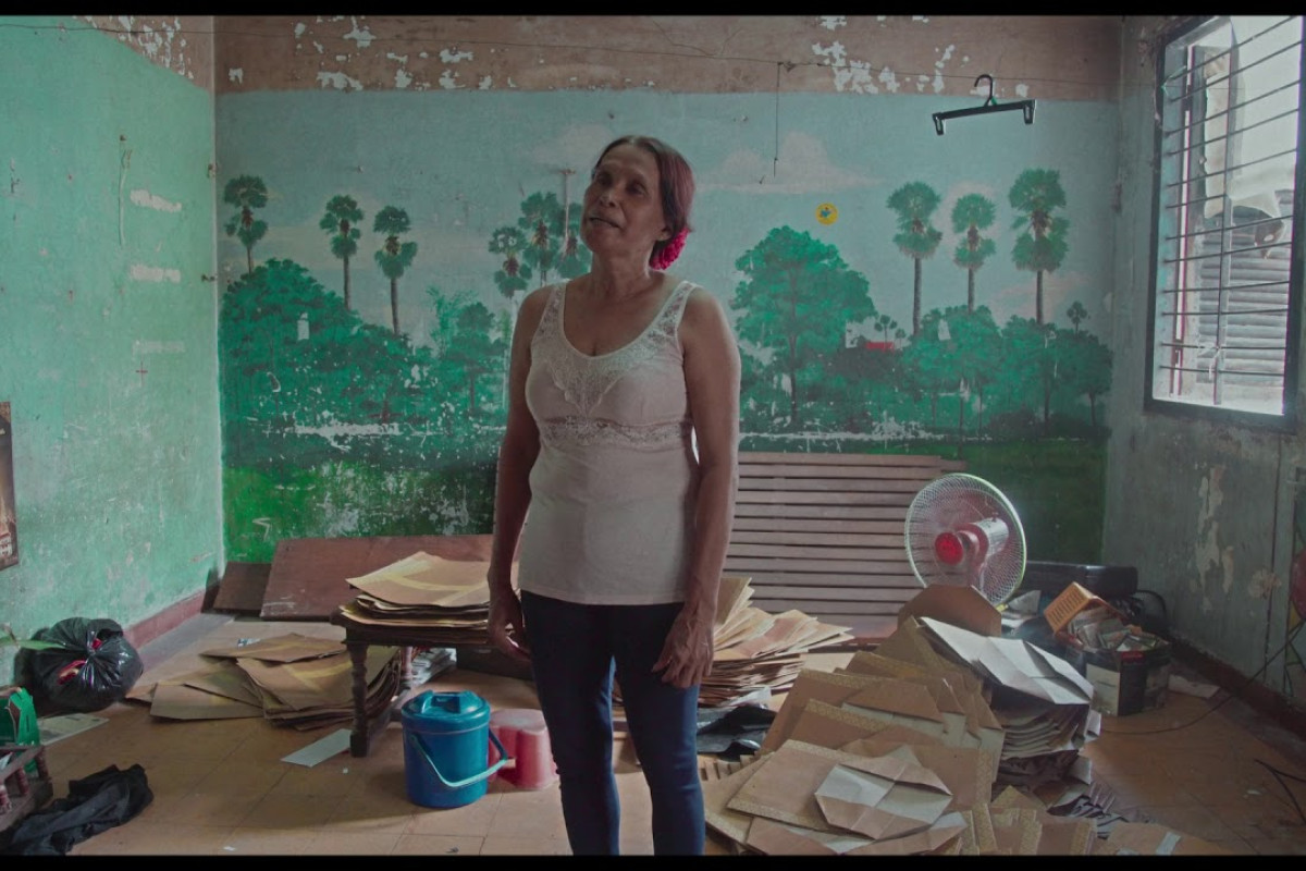 Woman stands in room that is disheveled with unfolded boxes.