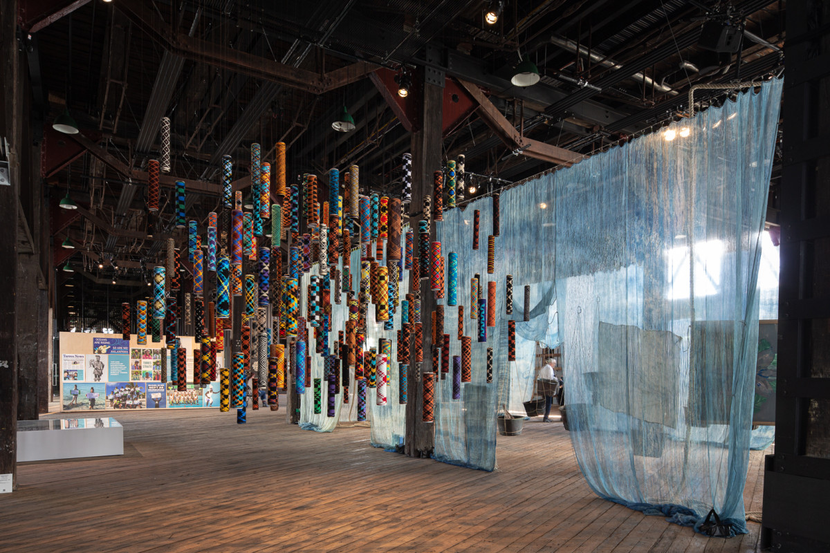 Many suspended cylindrical objects of many colours and patterns.