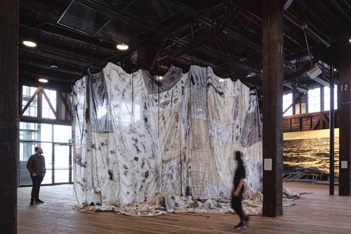Large textured fabric is draped from the ceiling of a warehouse location.