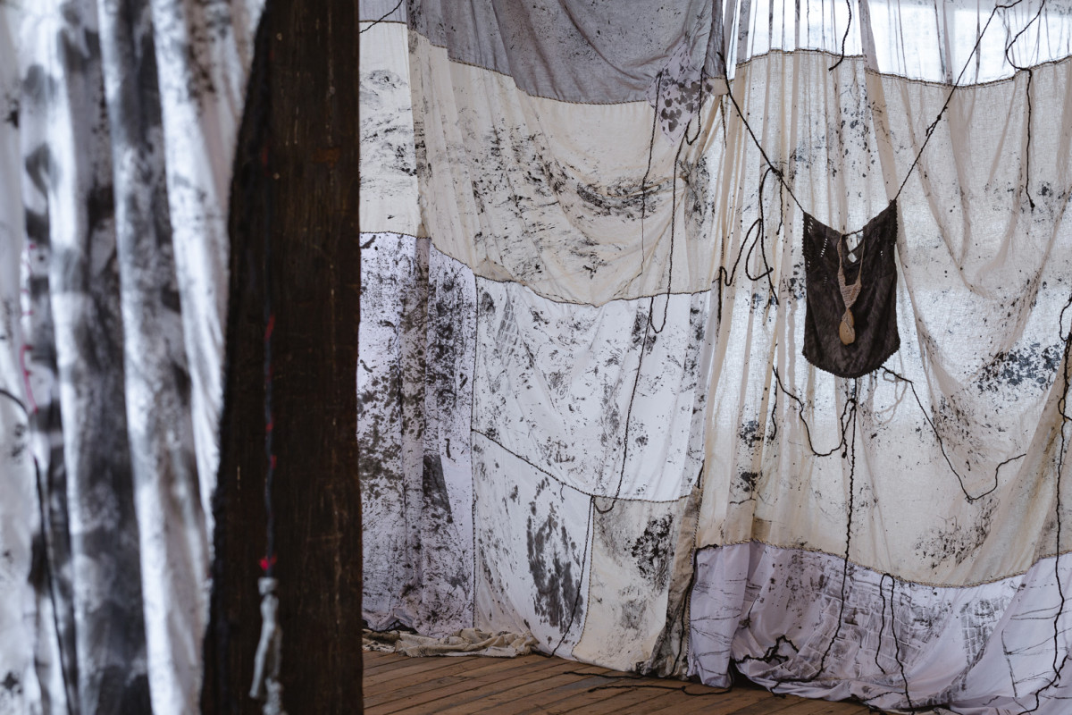 Large textured fabric is draped from the ceiling of a warehouse location.