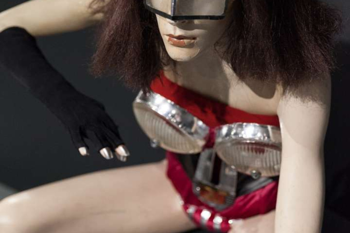 A mannequin wears a costume made up of elements representing car parts.