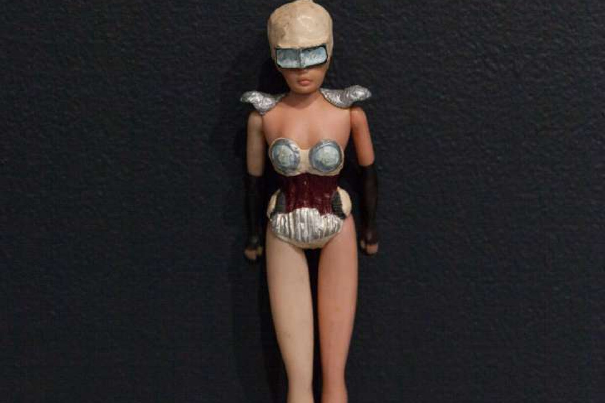 A Barbie Doll wears a costume made up of elements representing car parts.