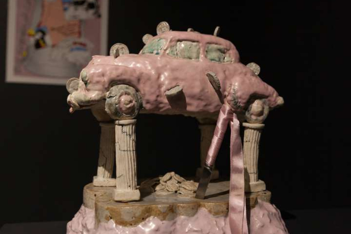 A pink, hand made sculpture of a car sitting on top of four columns
