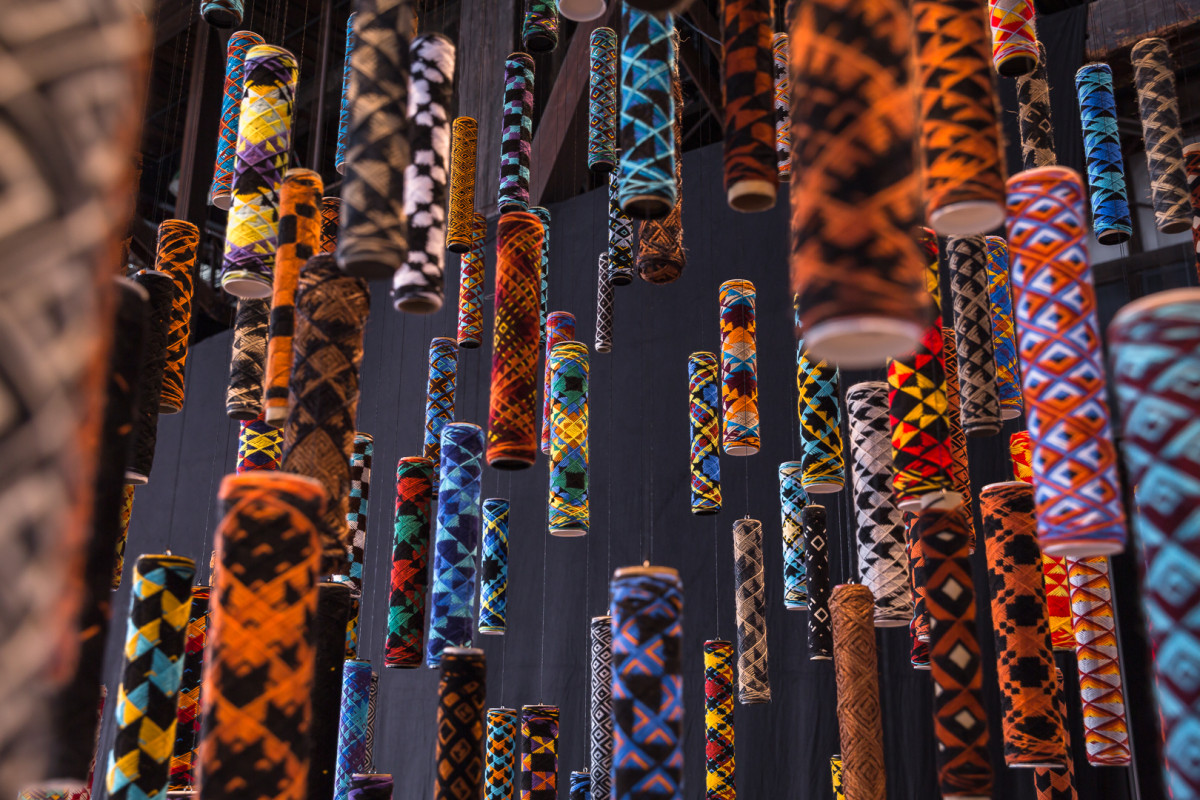 Many suspended cylindrical objects of many colours and patterns.