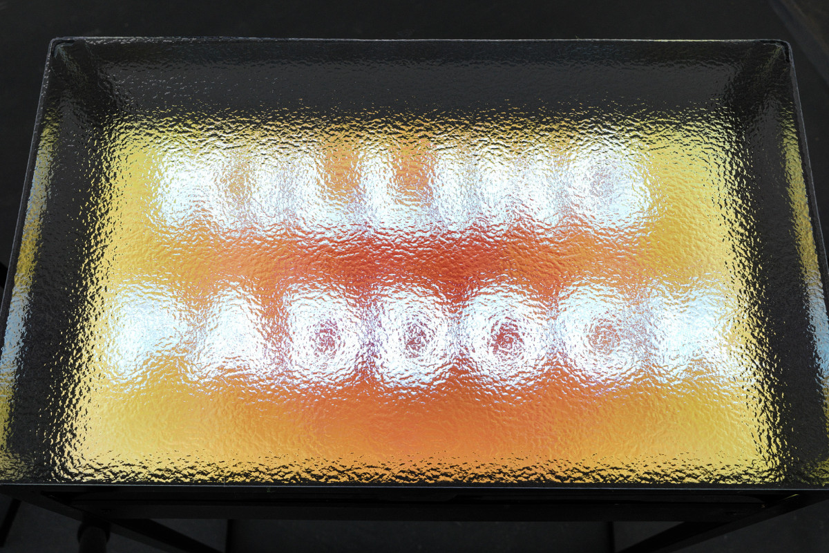Close up of sculpture with text reading 'killing paddock' seen through rippled glass.