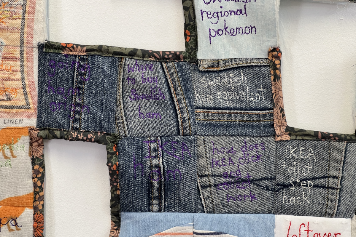A quilt made of denim and patterned fabric off-cuts embroidered with the artist's google search history.