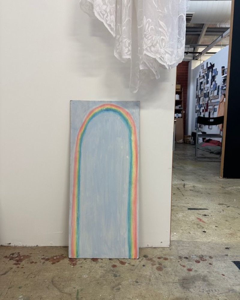 An oil painting of a rainbow on canvas sitting against a white wall in Abbey Murdoch's art studio.