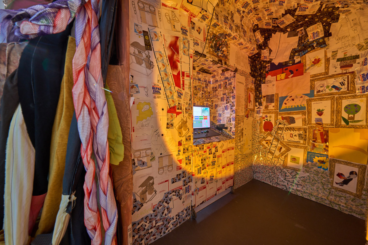 A photograph displaying the inside of Rockamora's head. The interior walls are collaged, and a screen and game console sit in the centre.