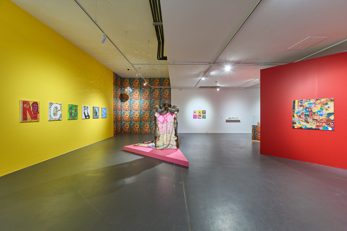 Wide view of exhibition install in ACE's gallery. A possum skin cloak sits upon a pink dais in the centre of the gallery.
