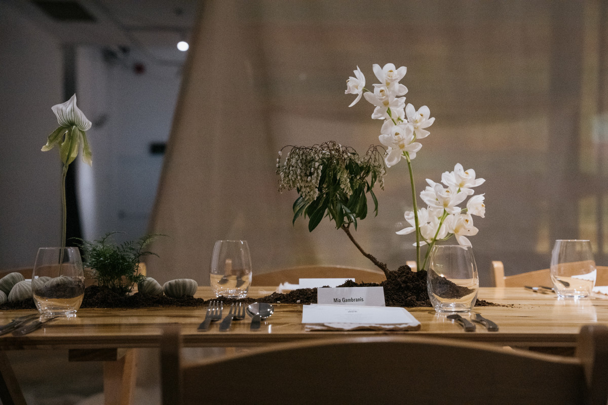 A part of a long table, adorned with a floral installation. Allison Chhorn's tent-like installation is in the background.