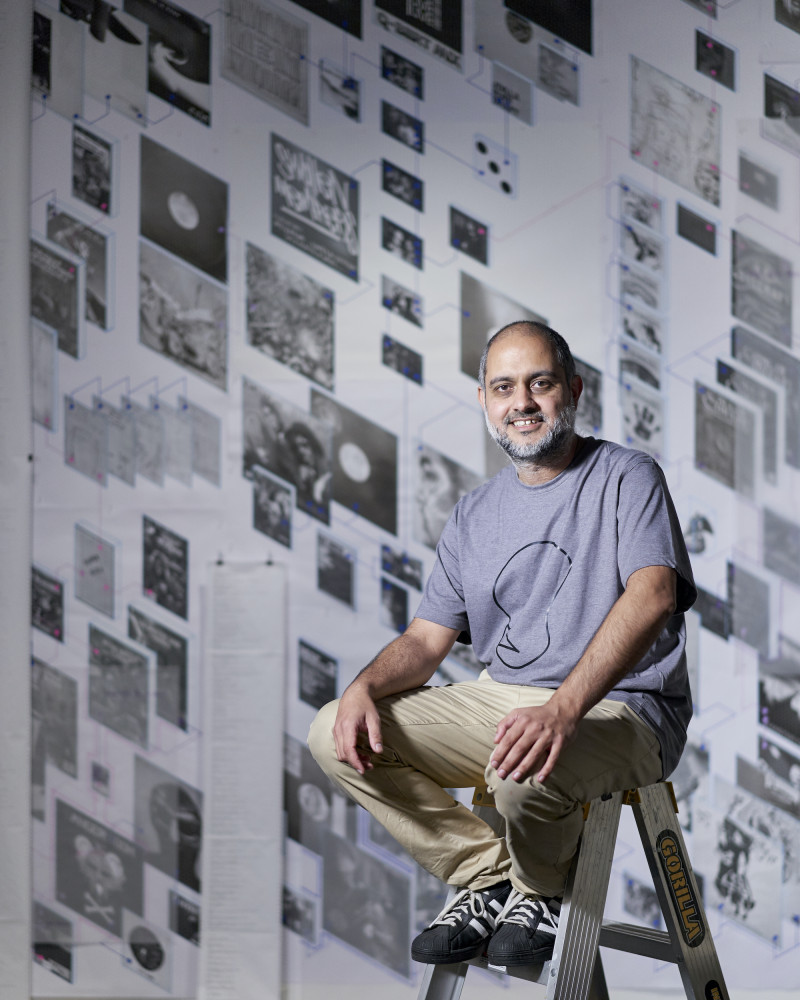 Portrait photograph of Roy Ananda sitting on a step ladder.