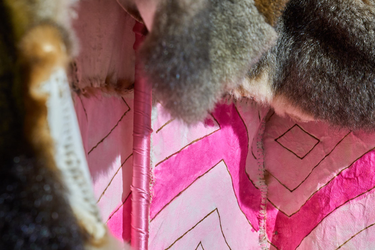 Inside detailed image of a cloak, which is made from possum pelts. The inside is patterned and pink.