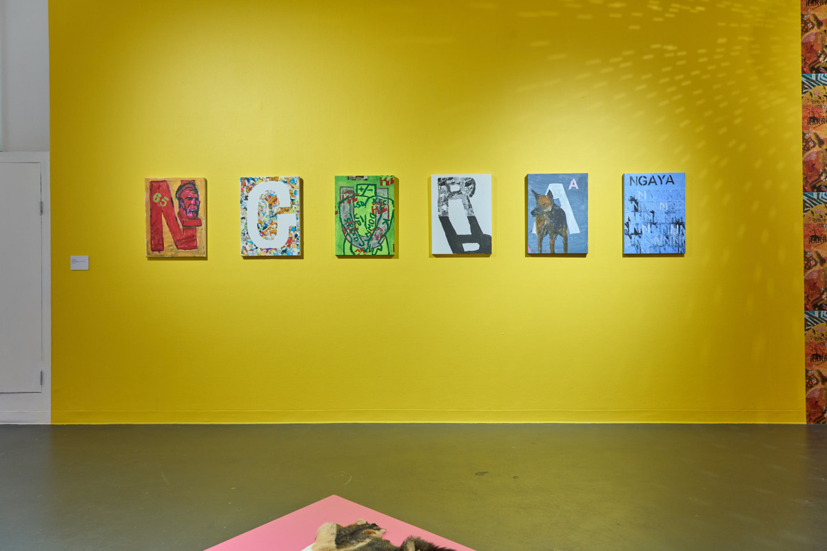 Six colourful artworks hang on a yellow wall, reflections from a disco reflect onto the art and wall.