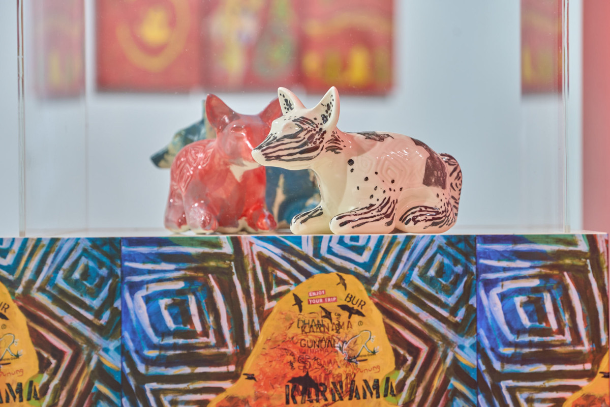 Three colourful ceramic dingos sit inside a glass vitrine.