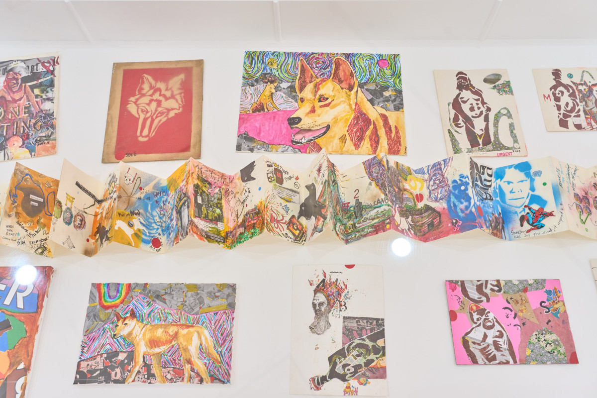 Several small colourful mixed-media collage artworks sit in a vitrine.
