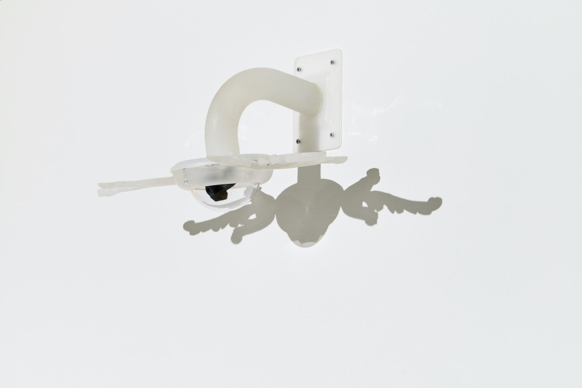 A security camera is metamorphosed into a winged angel with the addition of ornate resin wings.