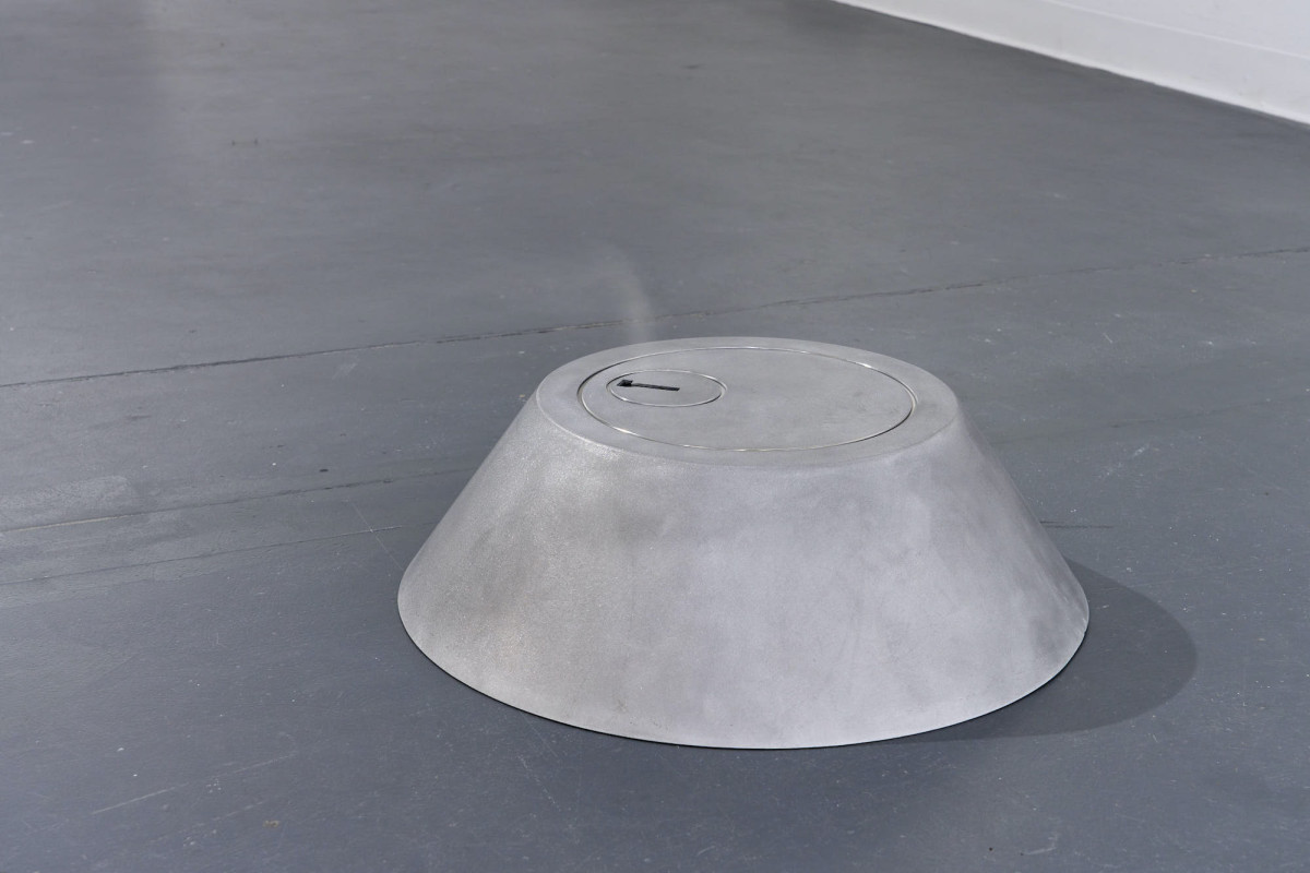 An oversized deadlock sits on the gallery floor, with the steam of an oil diffuser rising from the lock-hole.