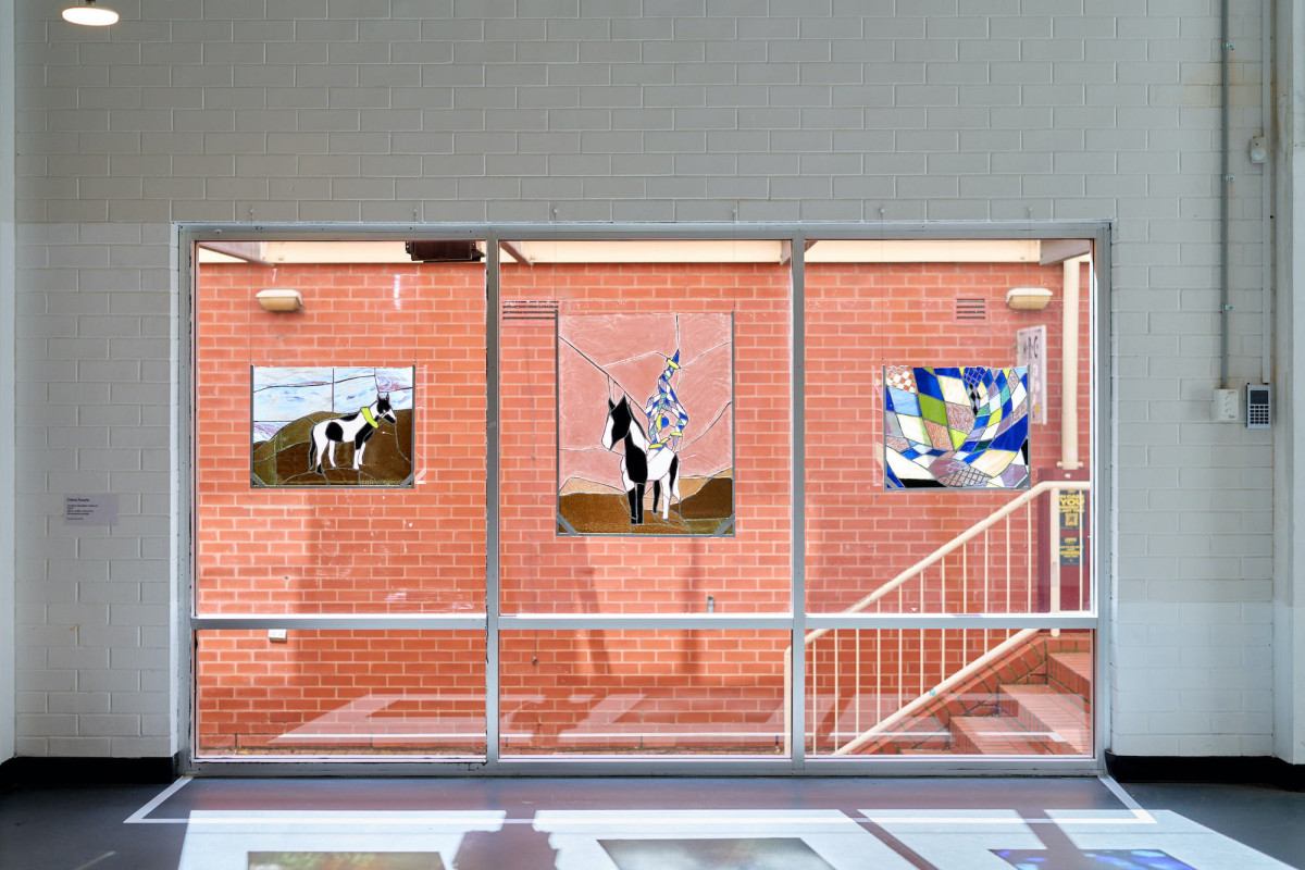 Three large lead-light works hang in a three-pane window in the front room at ACE.