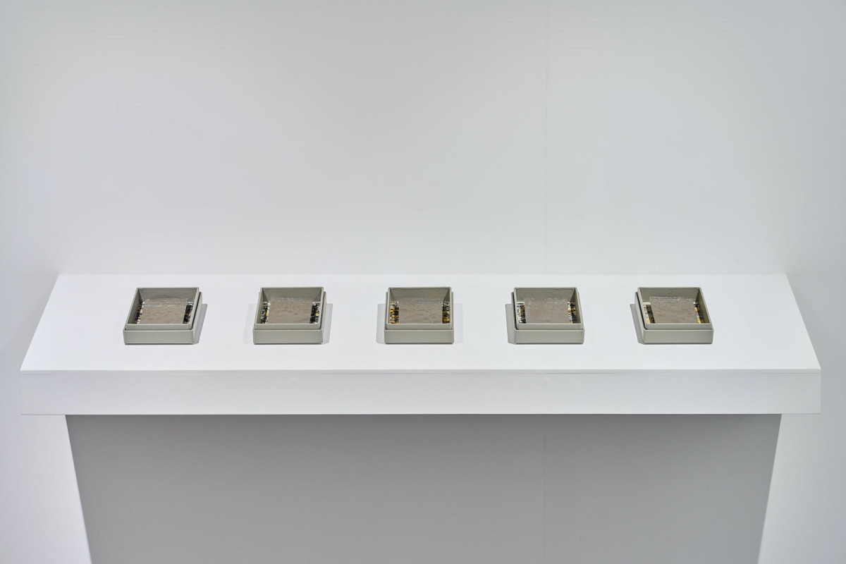 Five lead based works featuring marbled paper sit with archive boxes on a shelf in the gallery.