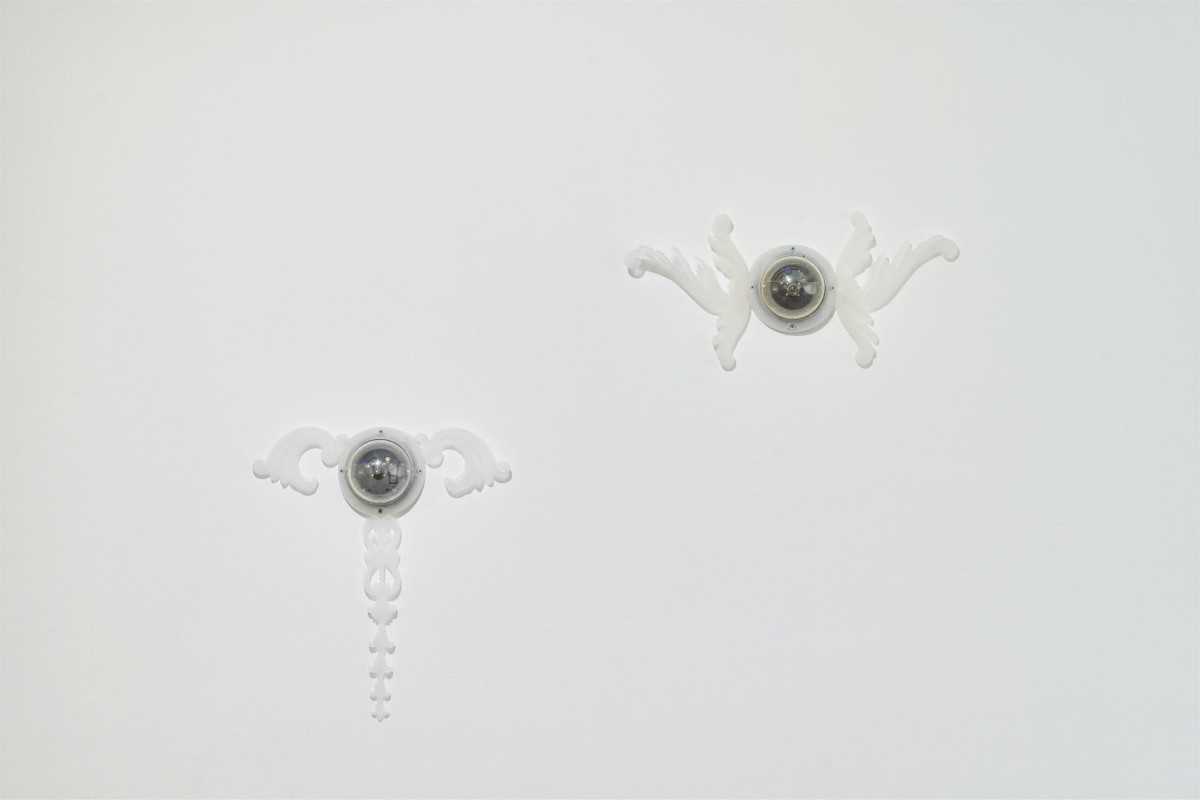 Two security cameras are metamorphosed into winged angels with the addition of ornate resin wings.