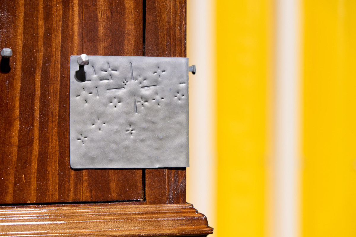 Detail of metal hammered with various sized small straight line indentations.