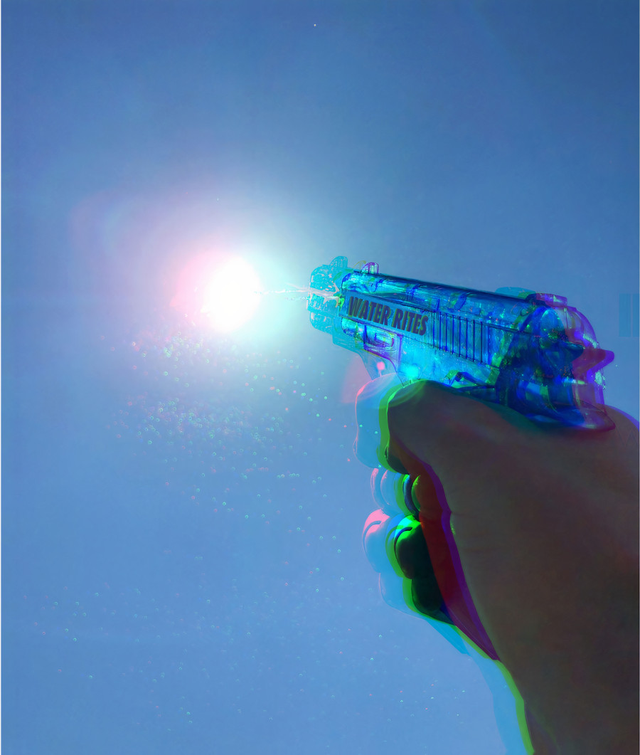 A hand shoots a water pistol into the sky, aimed at the sun.