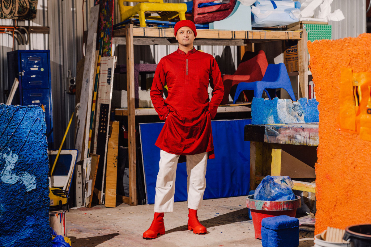 Kaspar stands in his colourful studio. He is wearing red and white clothes, and his hands are in his pant pockets.