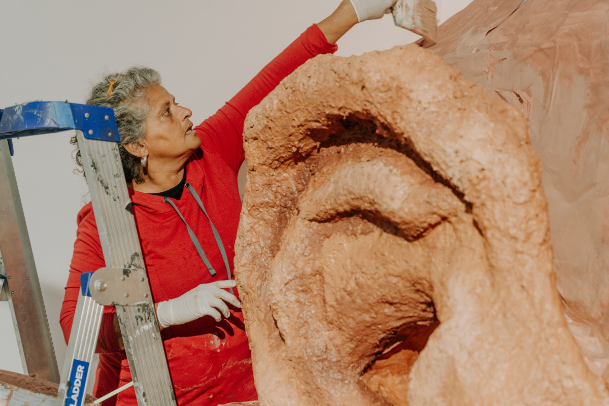 Koruna Schmidt Mumm reaching up to paint above Rockamora's ear.