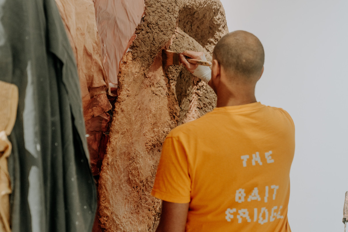 Kaspar Schmidt Mumm paints ear of Rockamora. His back is to the camera. His t-shirt says 'The Bait Fridge'.