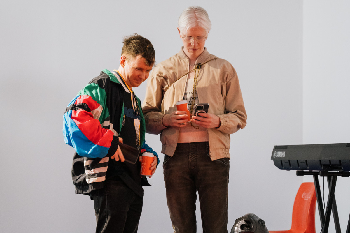 Opening night. 2 people smile and look at Truc's work.