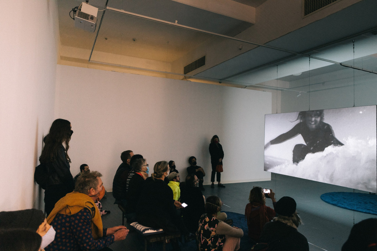 Audience watches video of surfer in the gallery.
