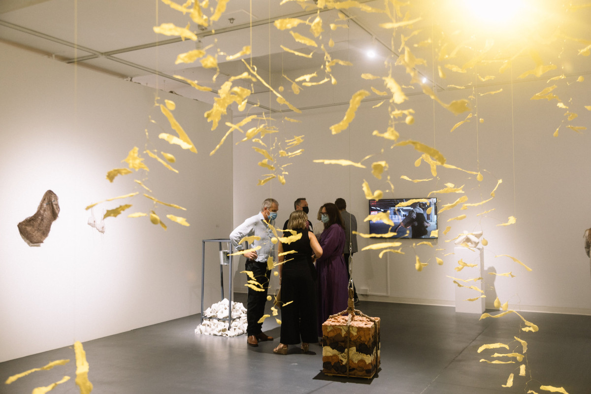 Audience views exhibition. Photographed through a hanging kelp-like mobile.