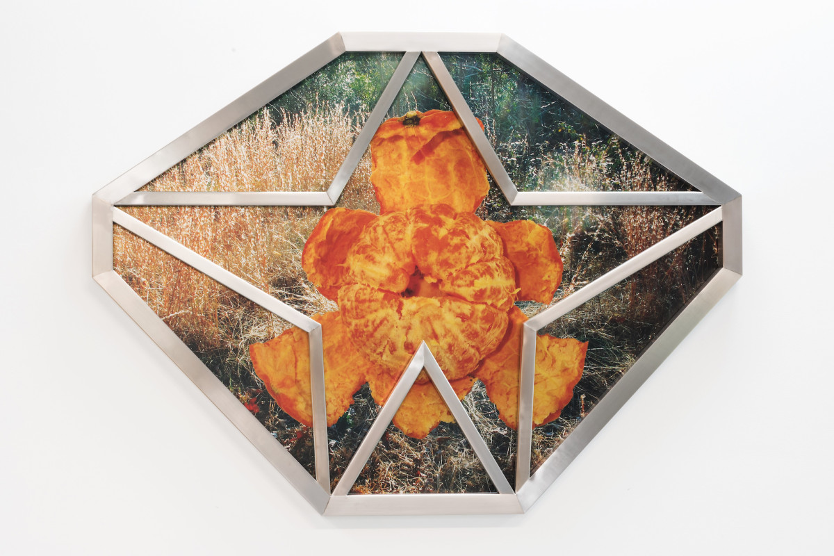 A round-shaped octagonal artwork featuring a mandarine and a chrome frame that incorporates a star.